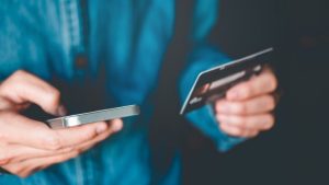 Person holding a credit card and mobile phone