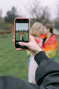 Someone taking a picture on a smartphone of a couple kissing