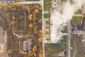 Drone image of trees and smoke coming from an industrial building